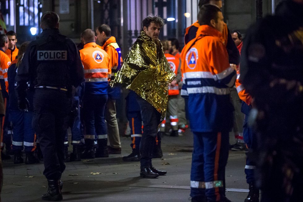 Foto LUSA - Um sobrevivente do atentado ao Bataclan Café, em Paris, a receber apoio das forças de emergência