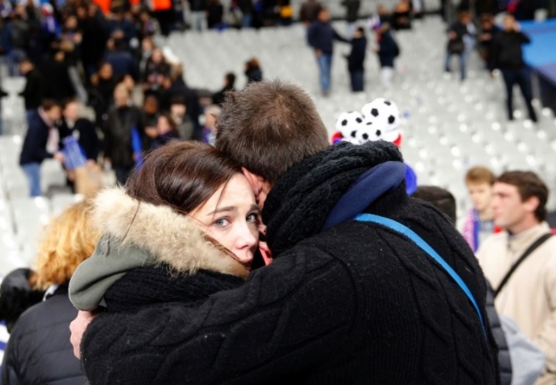 Foto: Christophe Ena / AP - Casal abraçado à saída do Stade de France, junto do qual teve lugar um dos atentados de Paris